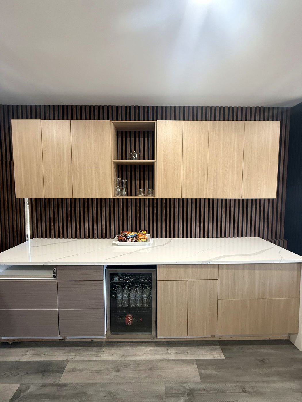 Light wood cabinetry and open shelving above a white quartz bar counter