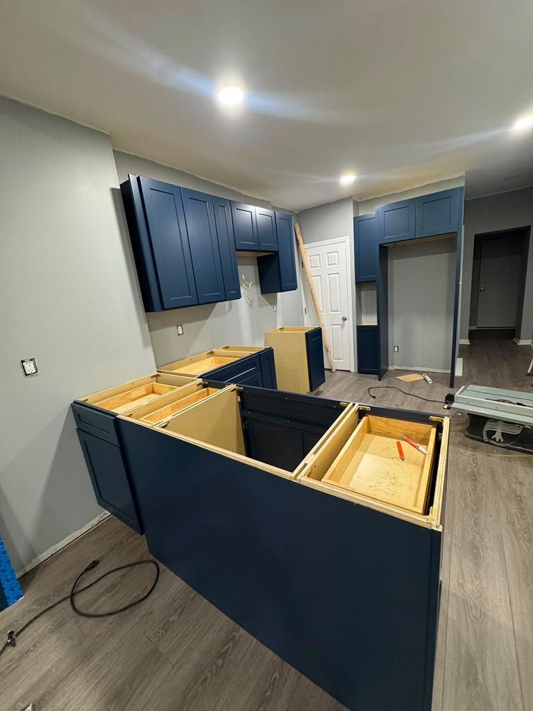 Navy shaker peninsula cabinets installed and levelled, open plywood tops ready for templating