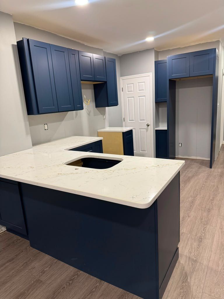 Navy shaker peninsula finished with a veined white quartz countertop