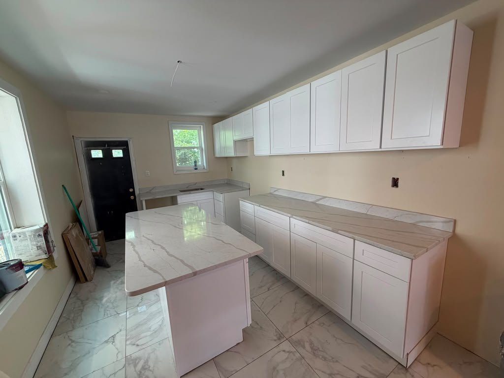 White shaker kitchen with a marble-look quartz island and a long perimeter counter