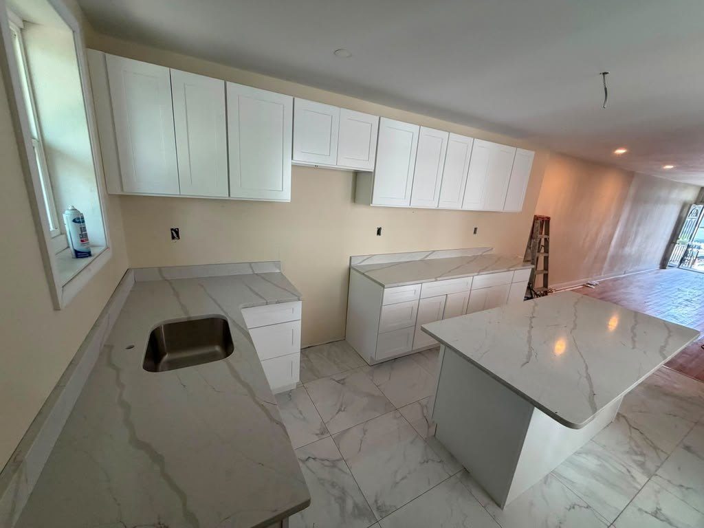 Marble-look quartz counter with an undermount sink cutout beside a waterfall island