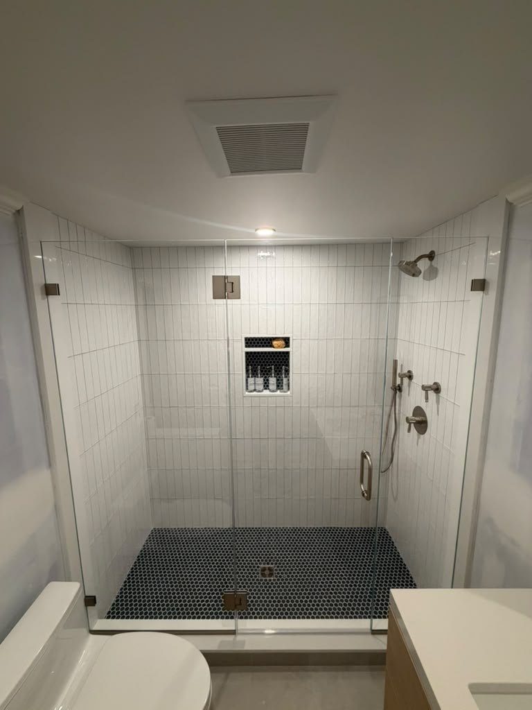 Bathroom vanity top in white stone beside a tiled walk-in shower