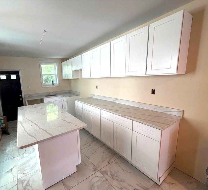 White shaker kitchen with a marble-look quartz island and a long perimeter countertop