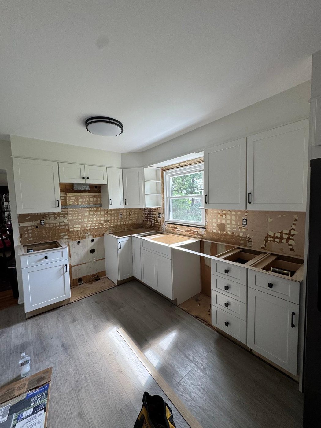 White shaker kitchen with the old backsplash stripped off and open cabinet boxes, before the countertops