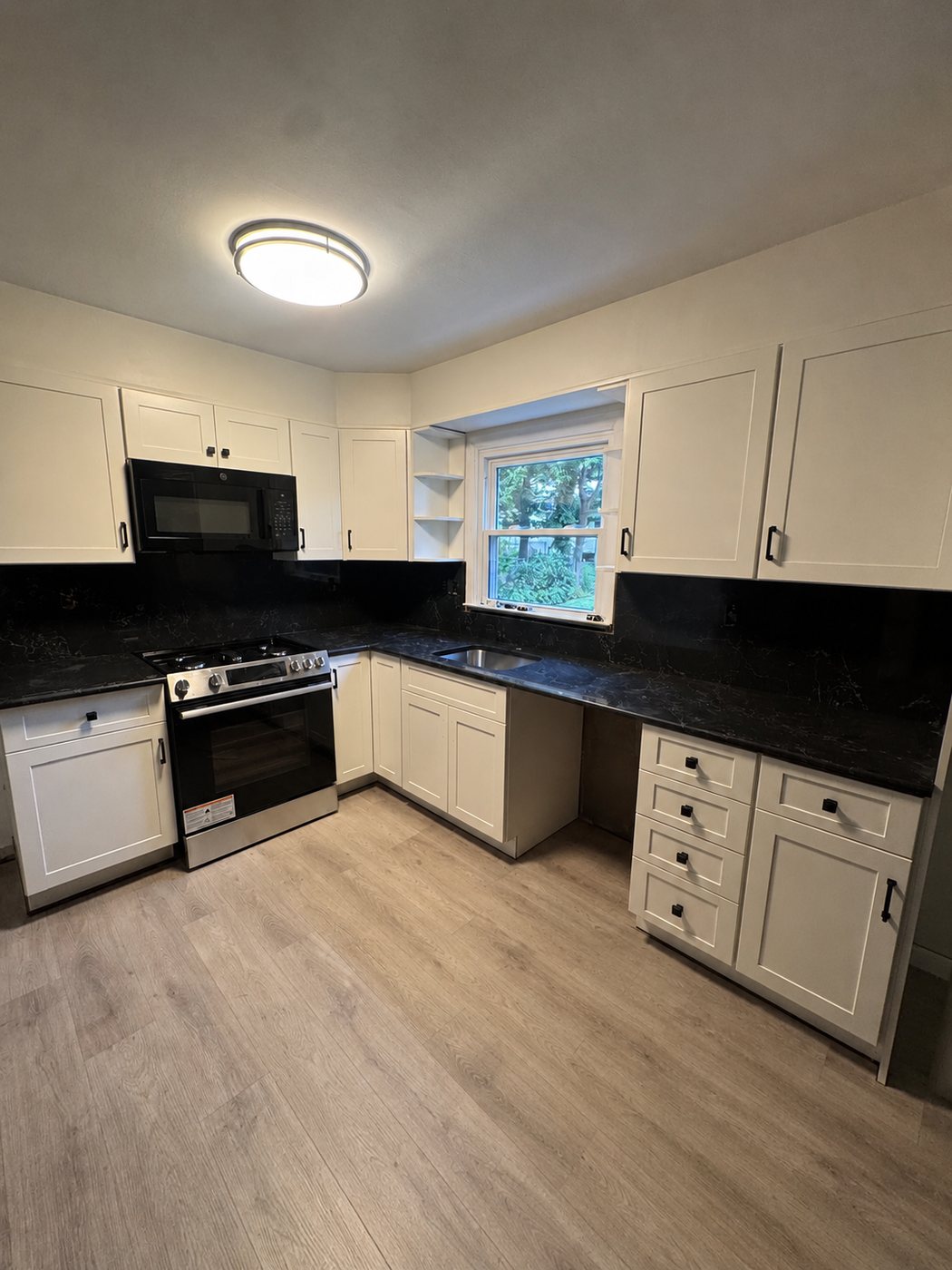 The same kitchen finished with black veined stone counters and a full-height backsplash