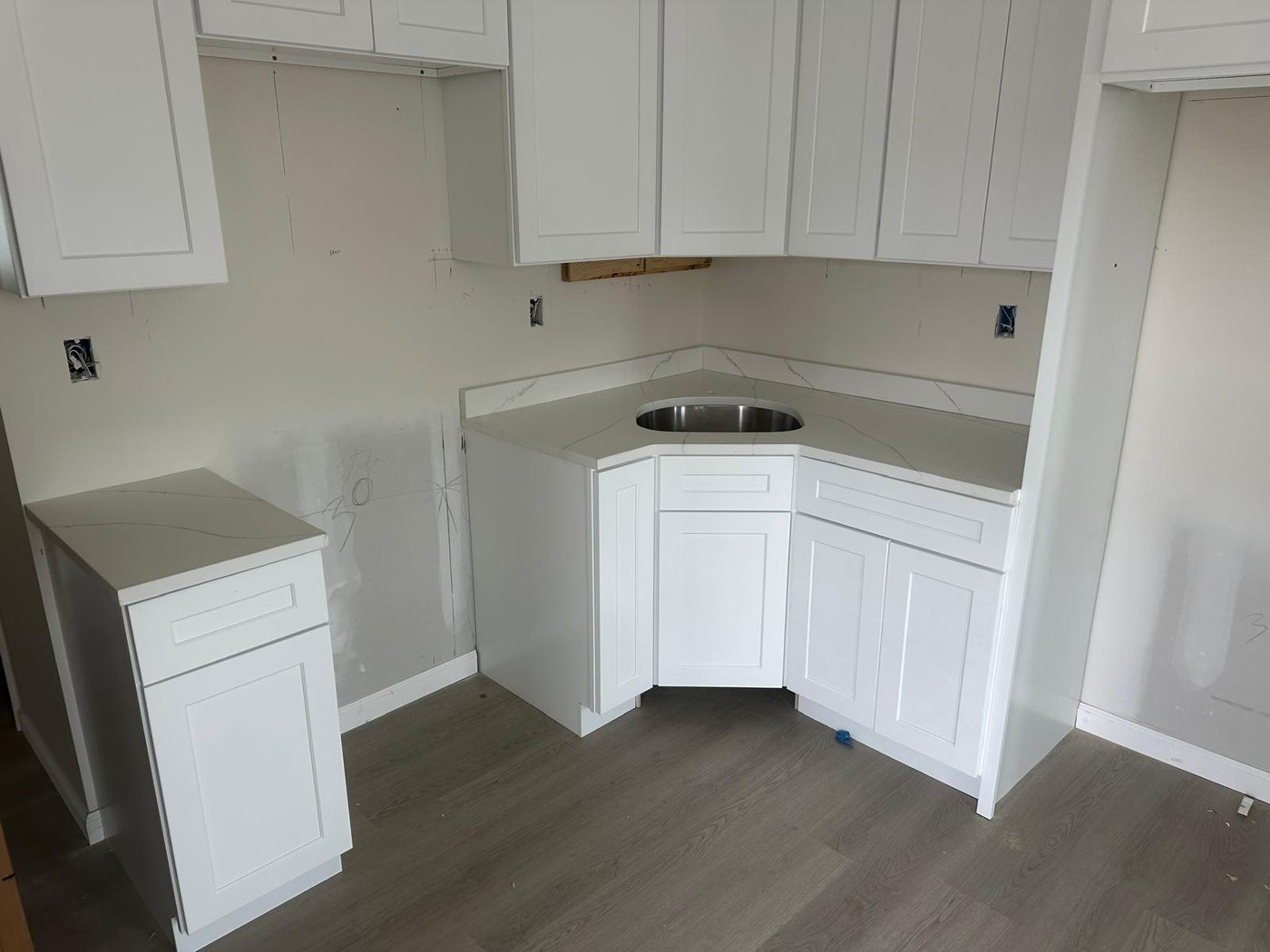 Veined white stone counter turning a corner with a round stainless bar sink cut into it