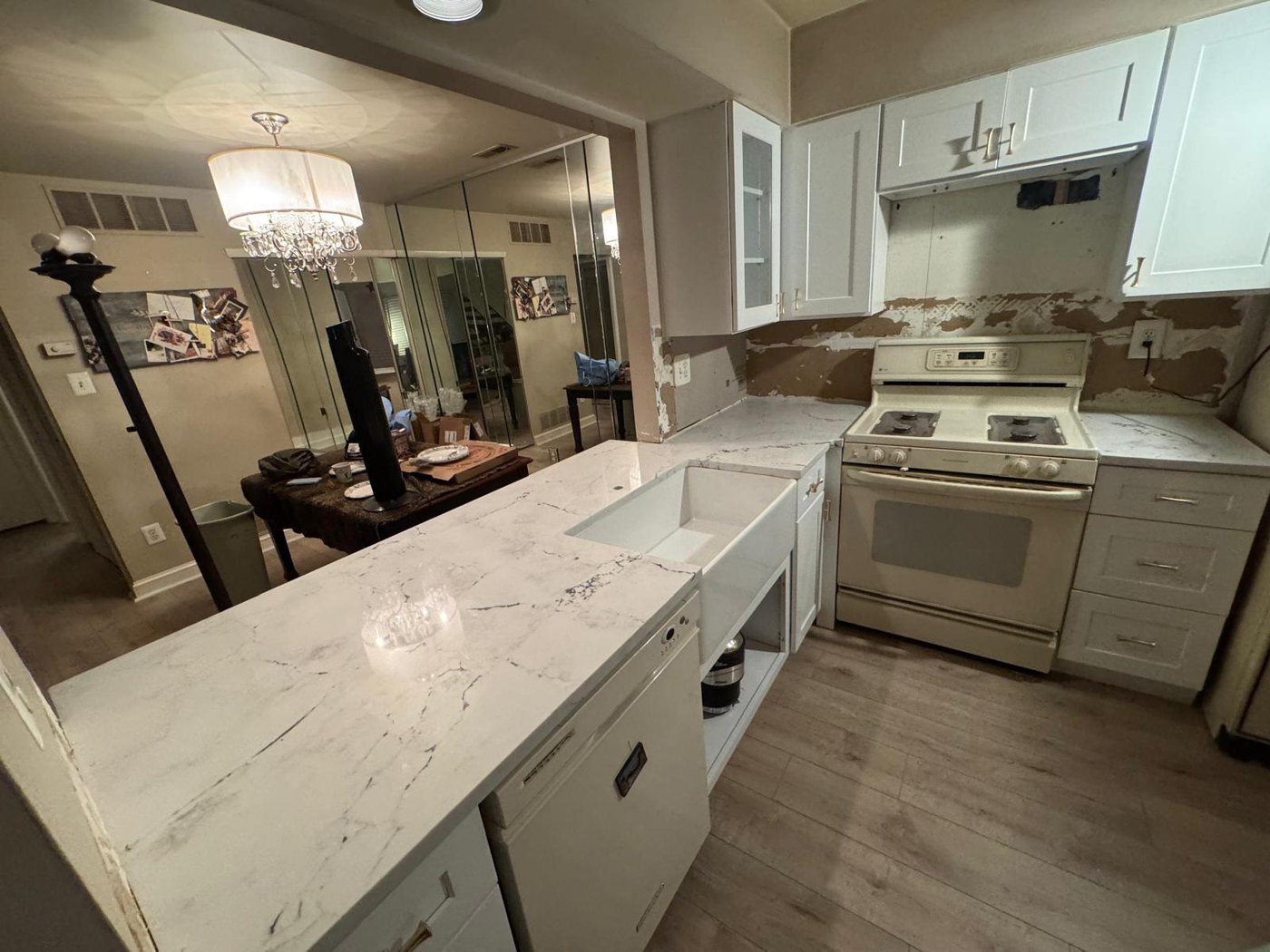 Long peninsula counter in veined white stone with a white apron sink set into the run
